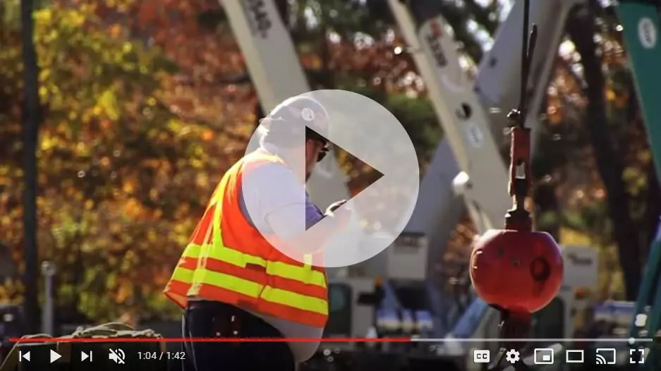 Video thumbnail of signalperson assisting with operating crane. He is wearing an orange and yellow safety vest.